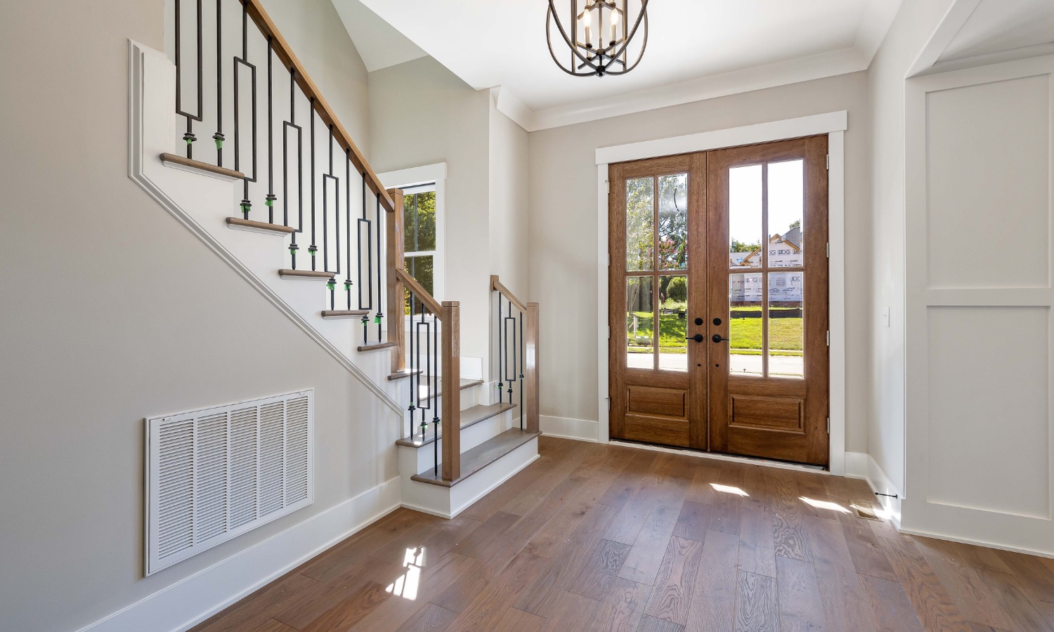 Elegant entryway featuring wooden double doors and a modern staircase, showcasing meticulous craftsmanship ideal for Bay Area home renovations by Bayside Builders Group.